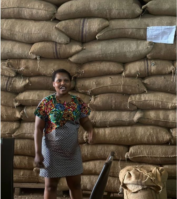 Oluwaseun Lijoka standing in front of stacked jute bags of cocoa in a warehouse